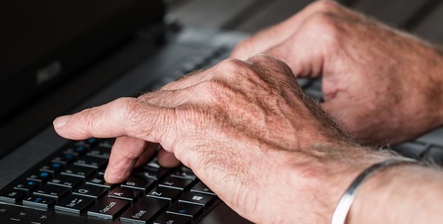 Alte Hände am Laptop schreibend